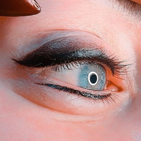Close-up van een oog met opvallende make-up en een lichtblauwe iris.